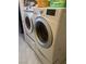 This laundry room includes white front load washer and dryer units on tile flooring at 6596 Secluded Ave, Las Vegas, NV 89110