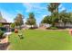 Spacious backyard with artificial grass, landscaping, and mature trees at 6715 Maple Mesa St, North Las Vegas, NV 89084