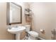 A half bath features a pedestal sink, mirror, and toilet in this home at 6715 Maple Mesa St, North Las Vegas, NV 89084