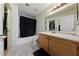 Bright bathroom with a shower over the tub, a vanity with wooden cabinets, and a large mirror at 675 Harbor Mist Ave, Henderson, NV 89015