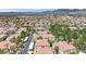An aerial view of a well-planned residential community with terracotta roofs and mature trees, with mountain and city views at 8408 White Eagle Ave # 101, Las Vegas, NV 89145