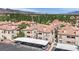 Aerial view showcasing a terracotta-tiled roofed apartment community with assigned covered parking, lush trees, and mountain views at 8408 White Eagle Ave # 101, Las Vegas, NV 89145