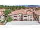 An apartment building featuring a terracotta tile roof with a red accent, surrounded by verdant trees and foliage at 8408 White Eagle Ave # 101, Las Vegas, NV 89145