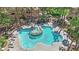 Aerial view of a uniquely designed swimming pool with tanning ledges, lush greenery and mature trees at 8408 White Eagle Ave # 101, Las Vegas, NV 89145