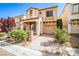 Inviting two-story home with a warm stucco exterior and landscaped front yard with driveway and attached garage at 9717 Villa Lorena Ave, Las Vegas, NV 89147