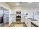 Modern kitchen featuring white cabinets, stainless steel appliances, quartz countertops, and barstool seating at 9966 Mystic Moss St, Las Vegas, NV 89183
