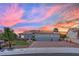 Beautiful single-story home with a tile roof, three-car garage, and manicured front yard at sunset at 10001 Cresent Creek Dr, Las Vegas, NV 89134