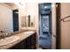 Hallway bath with double sinks, granite countertop, black and white tile flooring, and white cabinets at 12124 Kite Hill Ln, Las Vegas, NV 89138