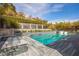 Beautiful pool area with built-in loungers, a nearby fire pit, and lush greenery at 12124 Kite Hill Ln, Las Vegas, NV 89138