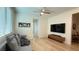 Bright living room with wood flooring, a ceiling fan, and a large TV for optimal viewing at 12428 Lincoln Creek Ave, Las Vegas, NV 89138