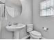 Well-lit half-bathroom with pedestal sink, round mirror, and modern fixtures showcasing practical elegance at 2116 Via Firenze, Henderson, NV 89044