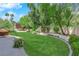 Lush backyard featuring green lawn, mature trees, and a patio area for outdoor seating at 240 Windsong Dr, Henderson, NV 89074