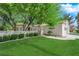 Landscaped front yard featuring a lush lawn, mature trees, and a decorative gate leading to the entrance at 240 Windsong Dr, Henderson, NV 89074