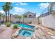 Backyard oasis with a pool, spa, rock features, mature trees, and green grass at 2595 Aviv Ct, Las Vegas, NV 89121