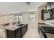 Modern kitchen features granite counters, black appliances, tile floor and island with sink at 2862 Starling Summit St, Henderson, NV 89044