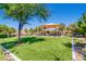 Community playground featuring a covered play structure, surrounded by lush green grass and mature trees at 2862 Starling Summit St, Henderson, NV 89044