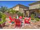 Inviting backyard with red Adirondack chairs circling a fire pit, complemented by lush landscaping and a covered patio at 2936 Aragon Terrace Way, Henderson, NV 89044