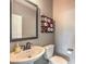 Charming half bathroom features sleek fixtures, decorative mirror, and playful tic-tac-toe toilet paper holder at 2936 Aragon Terrace Way, Henderson, NV 89044