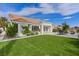 Well-maintained backyard with green grass, a paved patio area, and a charming white house with a tile roof at 3024 Lotus Hill Dr, Las Vegas, NV 89134