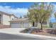 Tan two-story home with a three-car garage and drought-resistant landscaping at 3079 Evening Mist Ave, Henderson, NV 89052
