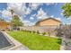 A backyard featuring well-kept green turf, an inviting pergola, and tidy garden beds along the surrounding brick wall at 325 Heather Dr, Henderson, NV 89002