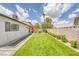 A spacious backyard featuring green turf, a pergola, and a neatly maintained garden bed along the perimeter wall at 325 Heather Dr, Henderson, NV 89002