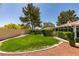Green backyard featuring a grassy area, mature landscaping, and a cozy patio at 4004 Nancy Margarite Ln, Las Vegas, NV 89130