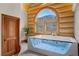 Luxurious bathroom featuring modern soaking tub with window views, and wood door at 4927 Snow White Rd, Las Vegas, NV 89124