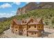 Striking log home with a stone foundation nestled in a mountain setting with a beautiful contrasting blue sky at 4927 Snow White Rd, Las Vegas, NV 89124