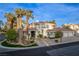 Elegant two-story home featuring a red tile roof, light exterior, a circular driveway and lush landscaping with palm trees at 4944 Spanish Heights Dr, Las Vegas, NV 89148