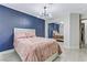 Bedroom featuring wooden floors, mirrored closet, modern lighting fixture and dark blue accent wall at 5045 Sock Hop Way, North Las Vegas, NV 89031