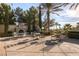Charming outdoor patio with stone fireplace, seating and tables surrounded by mature trees and manicured shrubs at 5078 Rivedro St, Las Vegas, NV 89135