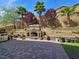 Serene backyard featuring a stone fireplace, mature trees, and landscaped details at 6975 Hopi Summit Ct, Las Vegas, NV 89149