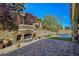 Outdoor kitchen and stone fireplace surrounded by lush landscaping at 6975 Hopi Summit Ct, Las Vegas, NV 89149