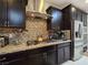 Kitchen featuring stainless steel appliances, granite countertops, a tile backsplash, and dark wood cabinets at 6975 Hopi Summit Ct, Las Vegas, NV 89149