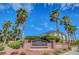 View of desert community entrance sign, featuring mature palm trees and lush landscaping at 7619 Belgian Lion St, Las Vegas, NV 89139
