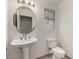 Well-lit half bathroom with pedestal sink, oval mirror, and modern toilet at 9048 Faversham Ct, Las Vegas, NV 89123