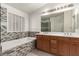 Bathroom with a double vanity, soaking tub with decorative tile surround and natural light at 9048 Faversham Ct, Las Vegas, NV 89123