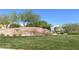 Entrance to 'The Mesa' features a decorative stone wall surrounded by vibrant green landscaping at 10349 Mystic Pine Rd, Las Vegas, NV 89135