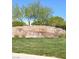 The Mesa community entrance featuring a stone wall and lush green grass at 10349 Mystic Pine Rd, Las Vegas, NV 89135