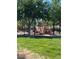 Community playground with modern equipment and shaded seating area surrounded by lush trees and green lawns at 10349 Mystic Pine Rd, Las Vegas, NV 89135