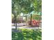 Community playground with covered seating area and modern equipment surrounded by lush trees and green lawns at 10349 Mystic Pine Rd, Las Vegas, NV 89135