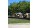 Community playground with modern equipment and shaded seating area surrounded by lush trees and green lawns at 10349 Mystic Pine Rd, Las Vegas, NV 89135