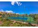 A community tennis court with a bright blue surface, surrounded by lush landscaping and community homes under a bright blue sky at 11178 Corsica Mist Ave, Las Vegas, NV 89135
