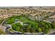 Aerial view of a community park with a grassy field, clock tower, playground, and surrounding homes at 11732 Del Sur Ave, Las Vegas, NV 89138