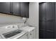 Bright laundry room features a white washer and dryer, black cabinets, and a convenient paper towel holder at 11732 Del Sur Ave, Las Vegas, NV 89138