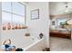 Well-lit bathroom showcasing a bathtub, window with decor, and open access to a bedroom area at 1204 Golf Club, Laughlin, NV 89029