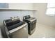 A bright laundry room featuring tile floors, overhead shelving, and modern appliances at 12101 Arrebol Ave, Las Vegas, NV 89138