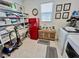 Organized laundry room featuring red fridge, washer, dryer, and shelving at 1288 Ventura Cliffs Ave, Henderson, NV 89012