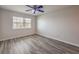 Light-filled bedroom showcasing wood-look floors, window with blinds, and ceiling fan at 1605 Colloquium Dr, Henderson, NV 89014